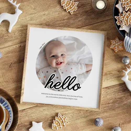 Baby photo wall art with circular design and text hello in light wooden frame on festive table