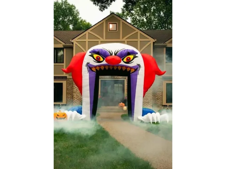 Inflatable clown arch halloween decoration with red hair and sharp teeth at house entrance.
