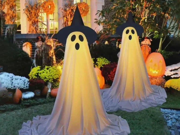 Illuminated ghost Halloween decorations with witch hats glowing in the garden