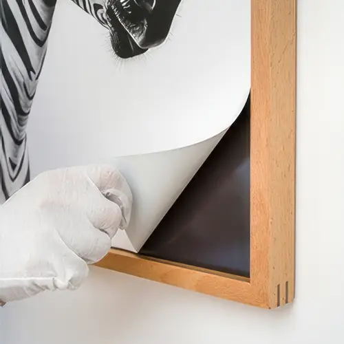 Close-up of rolled canvas art print showing natural timber frame and fine printing texture