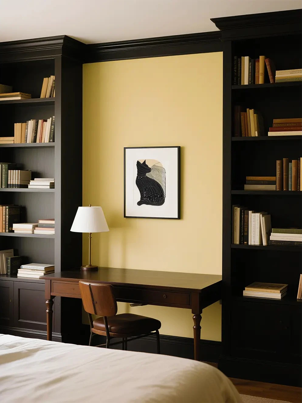 Black cat minimalist art print styled above a timber desk in a cosy home study with built-in bookshelves.
