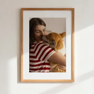 Woman hugging her corgi in a timber photo frame hanging on the wall
