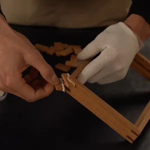 artisan inserting wooden tenons into a timber frame corner