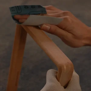 hand sanding the surface of a wooden picture frame