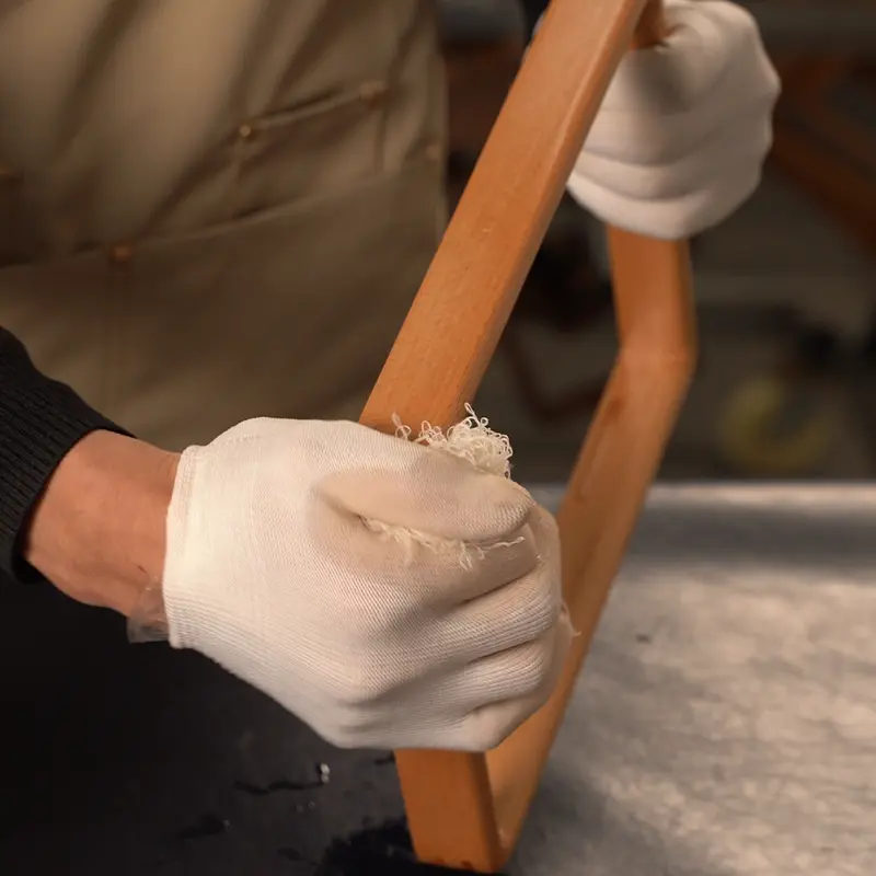 artisan polishing a wooden picture frame by hand