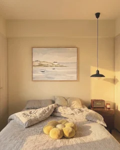 Textured coastal landscape artwork styled above a bed in soft warm lighting.
