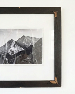An example of a photograph inside a standard budget frame that has severely rippled and wrinkled over time due to lack of professional mounting.