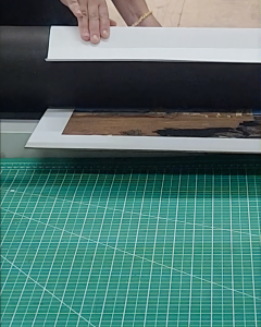 Professional adhesive mounting process where a photograph is permanently bonded to a backing board to ensure it remains flat and ripple-free.