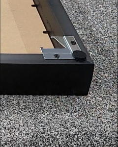 Close-up of a VeeArt frame back corner showing metal joinery hardware and a protective soft felt pad designed to prevent wall scratches.