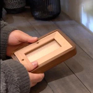 Hands holding a Veeart walnut solid wood photo frame horizontally, showing the light wood backboard and stand holes.
