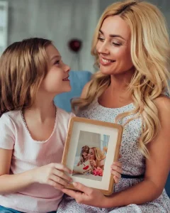 Mother and daughter holding a small beechwood framed wall art photo
