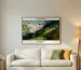 Horizontal landscape art by Arthur Streeton hanging 15-20cm above a light beige sofa in a cozy living room.