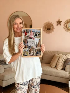 Woman holding a multi-photo collage frame in a living room.