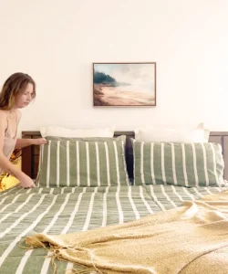 Framed landscape artwork centered above a striped bed set.